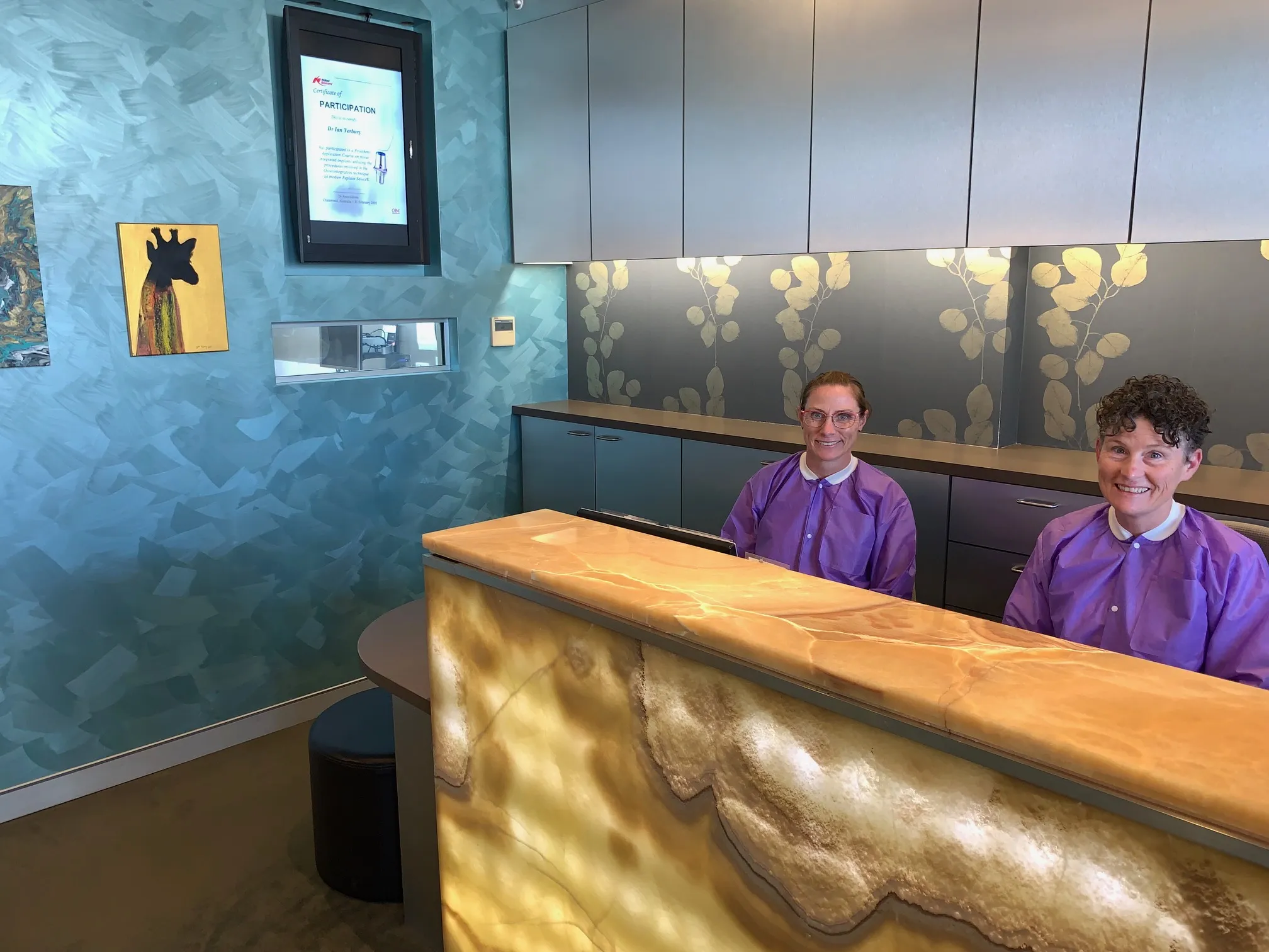 Reception area with two smiling staff members in purple shirts.